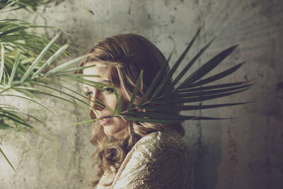 Woman with plant against wall