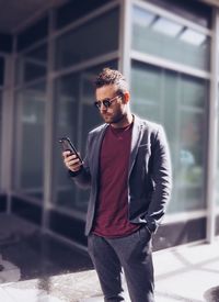 Handsome young man using mobile phone on footpath