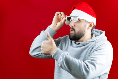 Midsection of man wearing sunglasses against red background