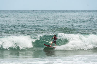 Man surfing in sea against sky