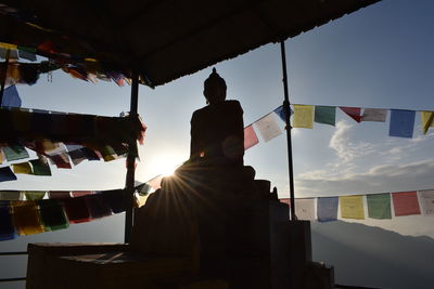 Low angle view of man relaxing at temple against sky