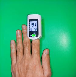 Close-up of human hand against blue wall