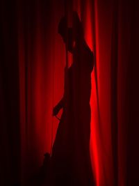 Shadow of woman seen through red curtain