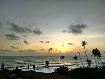 Silhouette of people on beach at sunset