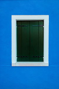 Window with white borders on blue dwelling wall