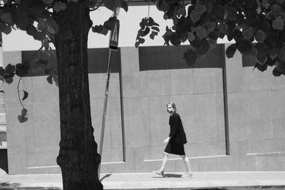 Side view of man standing by tree trunk