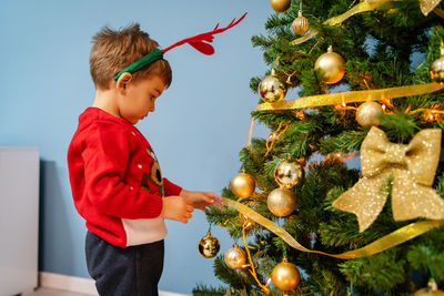 Cute boy standing by christmas tree at home