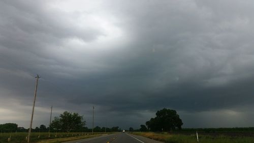 Road passing through landscape against cloudy sky