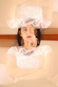Double exposure of thoughtful young woman sitting at home