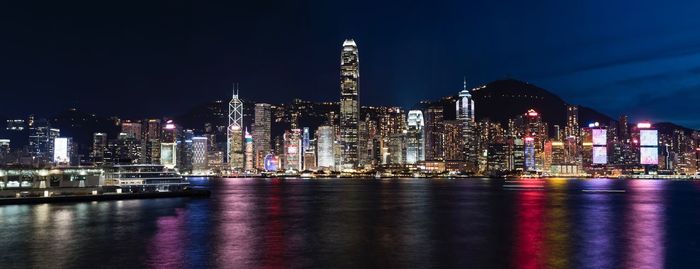 Panoramic shot of illuminated city by river at night