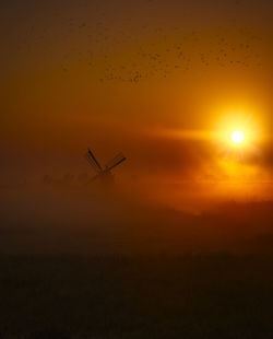 Silhouette airplane flying in sky during sunset