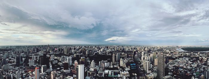 High angle view of city buildings against cloudy sky