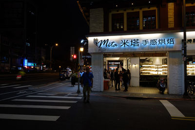 People walking on illuminated city at night