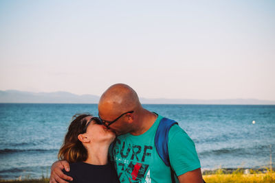 Couple kissing against sea