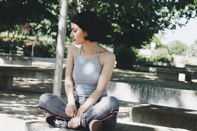 Young woman looking away while sitting on bench