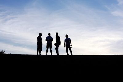 Silhouette men standing on field against sky