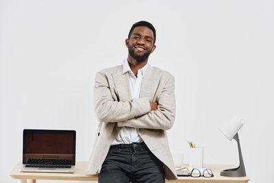 Young man using laptop while standing against white background