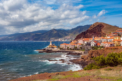 Scenic view of sea by buildings against sky