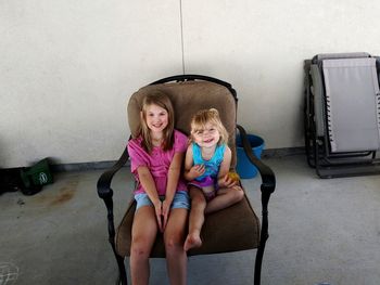 Portrait of a smiling girl sitting against wall
