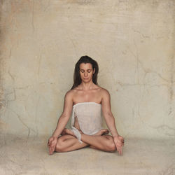 Young woman sitting against wall