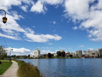 View of buildings by river against cloudy sky