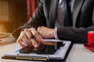 Midsection of businessman using digital tablet on desk
