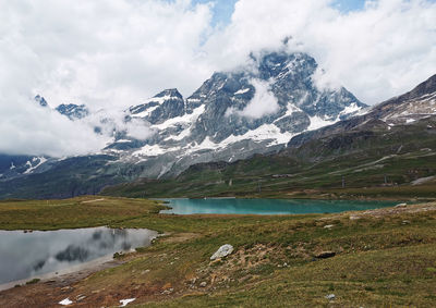Scenic view of mountains and lake against cloudy sky