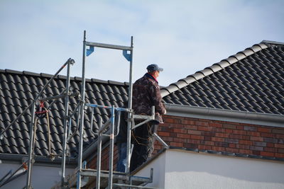 Workers standing on platform by roof of house