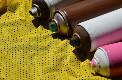 High angle view of aerosol cans on yellow textile