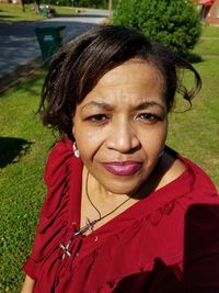 Close-up portrait of smiling mature woman standing in park during sunny day