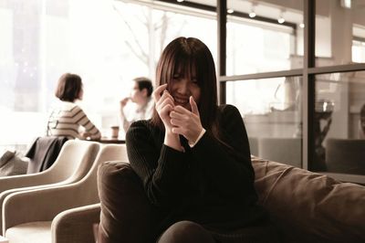 Portrait of woman sitting on sofa in cafe