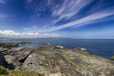 Scenic view of sea with rocky shore against blue sky