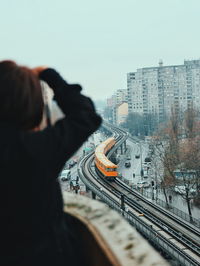 Rear view of man on railroad track against sky