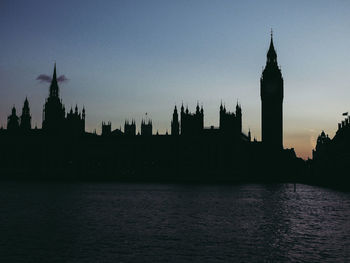 Silhouette buildings against sky at dusk