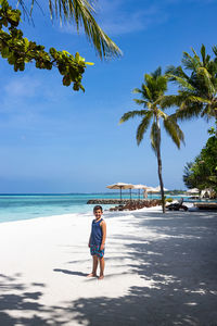 Little kid on a white sand beach with palm trees