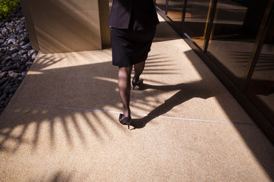 Low section of woman walking in corridor during sunny day