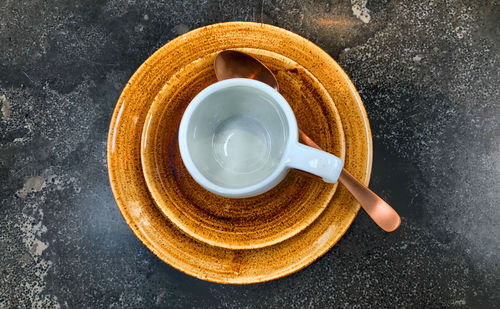 Empty white coffee or tea cup on a brown saucer on dark table background