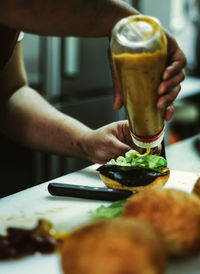 Close-up of hand preparing a burger