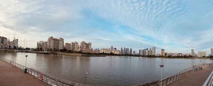 Bridge over river by buildings in city against sky