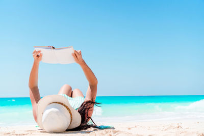 Woman reading book while reading book at beach