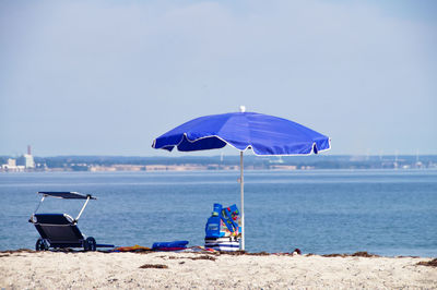 Parasol and chair at beach against sky