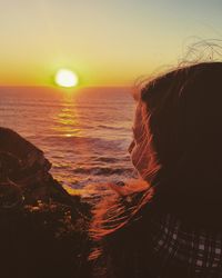 Rear view of woman at beach during sunset