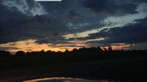 Silhouette trees on field against sky at sunset