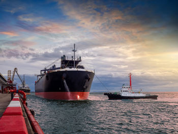 Commercial dock by sea against sky during sunset