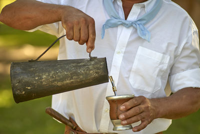 Midsection of person holding yerba mate drink . mate is a hot drink typical of latin america 