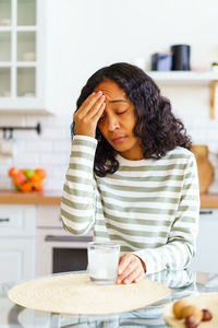 African-american female dealing with headache. dissolving pill in glass of water