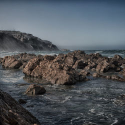 Scenic view of rocks in sea against sky