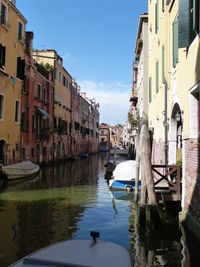 Canal amidst buildings in city against sky