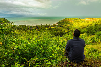 Rear view of man looking at sea against sky