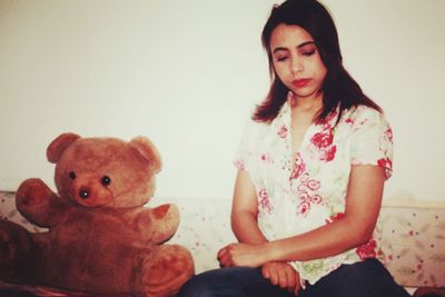 Full length of young woman sitting with toy